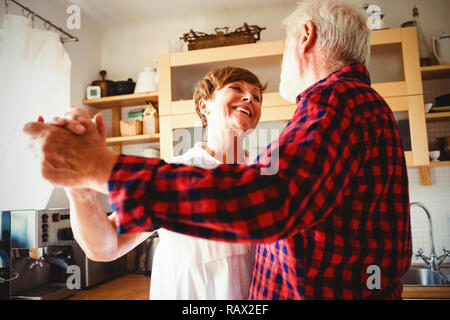 Senior couple dancing together in kitchen Stock Photo