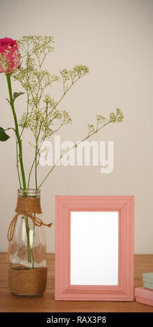 Rose flower in glass vase, photo frame and gift boxes on a table Stock Photo