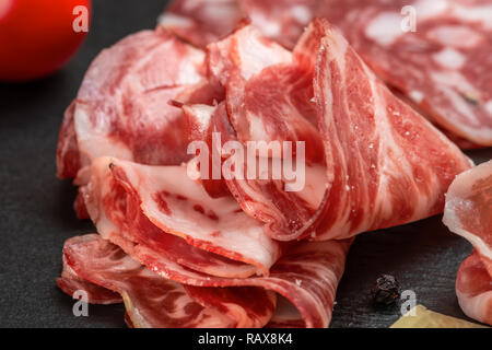 antipasto with sliced salami, cheeses, prosciutto, ham, tomato on black slate background Stock Photo