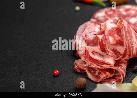 antipasto with sliced salami, cheeses, prosciutto, ham on black slate background, copy space Stock Photo