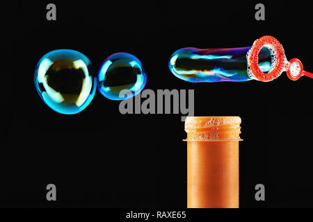 Colored Soap bubbles and orange blower on a black background Stock Photo