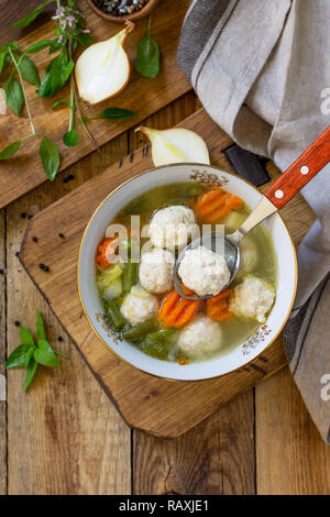 The concept Diet menu. Healthy soup with vegetables and chicken meatballs in a bowl on wooden table in rustic style. Top view flat lay background. Cop Stock Photo