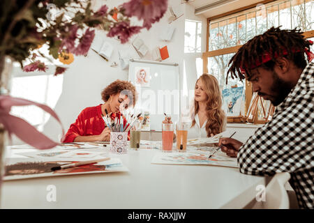 Three art students feeling busy while drawing in decorated studio Stock Photo