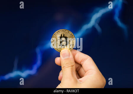 Man holding Bitcoin gold coin in front of lightning network concept background Stock Photo