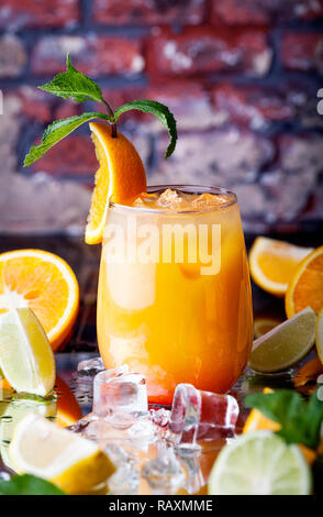 Orange cocktail with ice cubes in the tropical bar at brick wall background Stock Photo