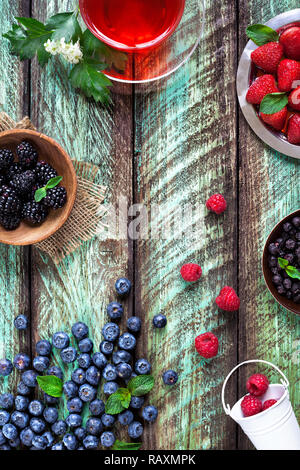 Herbal tea and various different berries on green rustic background in summer time Stock Photo