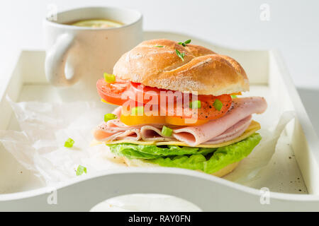 Tasty sandwich with cheese, ham and tea on white table Stock Photo