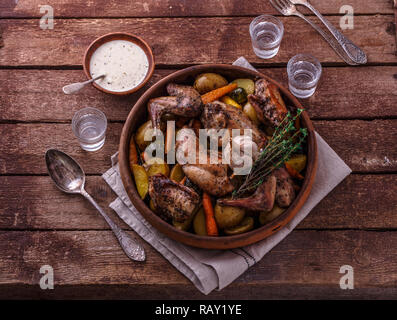 Oven baked rabbit with root vegetables and herbs, rustic style. Stock Photo