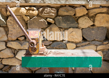 Old vise clamp bench with stone wall in the background. Stock Photo