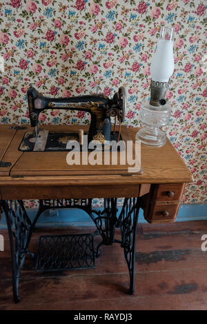 Vintage  Singer  Treadle Sewing Machine & antique glass parlour lamp on wooded table with vintage Victorian wallpaper. Historic Home, McKinney, Texas. Stock Photo
