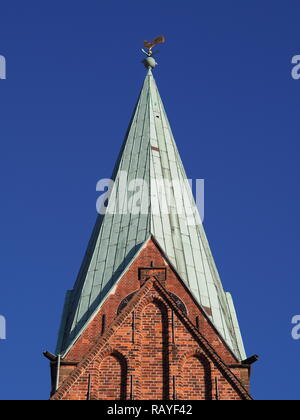 Bremen, Germany - Spire of St. Martini church with red brick walls, green copper roof, weather vane and blue sky in the background Stock Photo