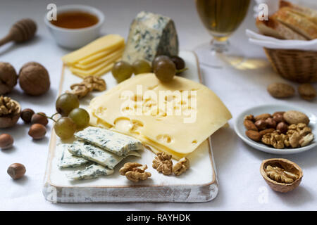 Appetizers of various types of cheese, grapes, nuts and honey, served with white and red wine. Rustic style. Stock Photo