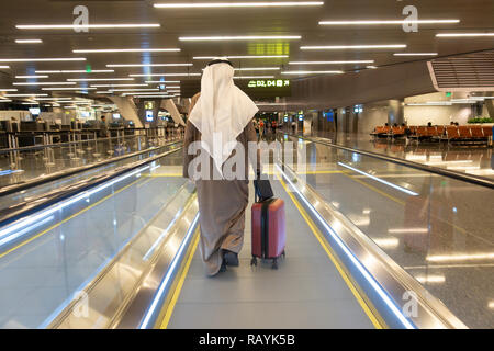 Arab passenger on moving walkway in terminal building at modern Hamad International Airport in Doha, Qatar Stock Photo