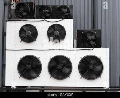 closeup photo of wall filled with rows of industrial air conditioner unit HVAC climate control system with huge fans Stock Photo