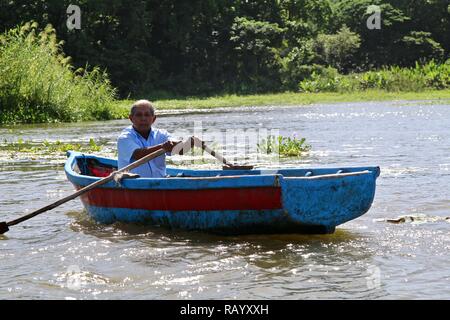 An old Nicaraguan man rowing his small wooden boat on Lake Nicaragua Stock Photo