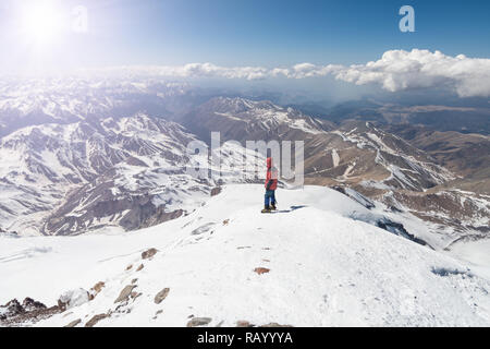 Climber stands at the top of Elbrus 5642m and looks at the mountains Stock Photo