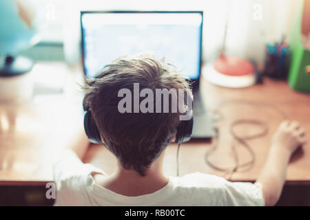Little dependent gamer kid playing on laptop indoors Stock Photo