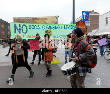 Protestors matching down Deptford High Street,  passing by a large banner against social cleansing, infront of Deptford Library, in   Deptford High Street.  During a campaign to save Reginald House and Old Tidemill Wildlife Garden, from destruction by Lewisham Council,  Deptford, Lewisham, South East London. Stock Photo