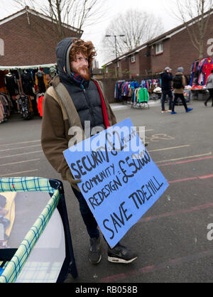 A Protestor carrying a banner at  Deptford Market, complaining about money being wasted on security measures,  just off  Deptford High Street,  during a campaign to save Reginald House and Old Tidemill Wildlife Garden, from destruction by Lewisham Council,  Deptford, Lewisham, South East London. Stock Photo