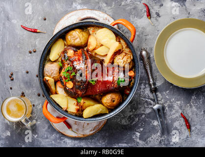 Pork knuckle on wooden surface.Roasted pork knuckle with potatoes Stock Photo