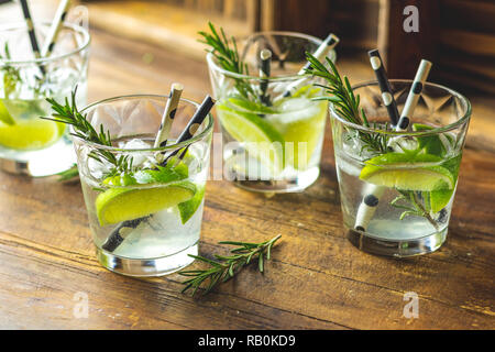 Fresh cocktail with lime, ice and rosemary, mojito cocktail in a bur on a rustic table, selective focus, shallow depth of the field. Stock Photo