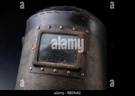 An old mask for the welder. Accessories for a production worker. Dark background. Stock Photo