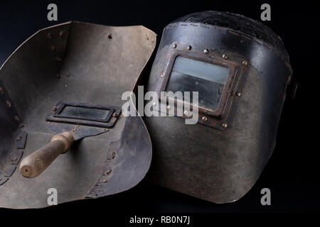An old mask for the welder. Accessories for a production worker. Dark background. Stock Photo