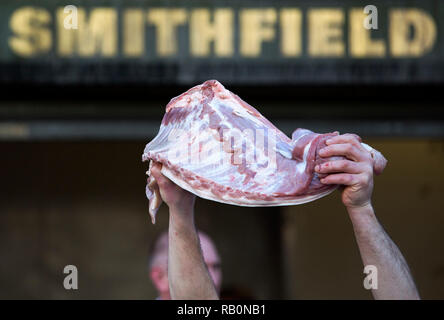 A butcher holds meat to sell during the annual Christmas Eve auction at Smithfield Market in the City of London.. Stock Photo