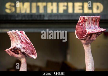 A butcher holds meat to sell during the annual Christmas Eve auction at Smithfield Market in the City of London.. Stock Photo