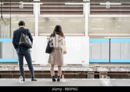 Asia Business concept for real estate and corporate construction - Asia business woman and man stand on train platform in background in Tokyo, Japan Stock Photo