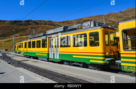 Grindelwald, Switzerland - Oct 20, 2018. Yellow and green Bernese Oberland Railway train stopping at Grindelwald train station platform. Stock Photo