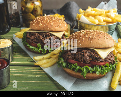 Barbeque pulled beef sandwich, burger, french fries, sauce, dark beer, corn on a wooden tray Stock Photo