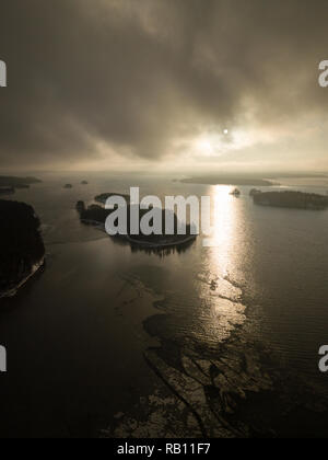 Dark clouds over freezing lake with islands. Sunset time aerial shot. Stock Photo