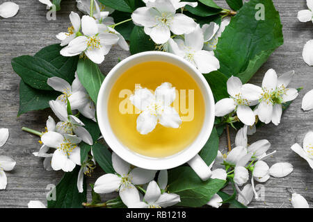 Cup of tea with jasmine flowers on a wooden background. top view Stock Photo