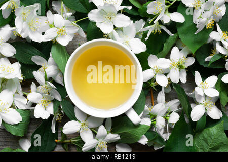 Cup of green jasmine tea on jasmine flowers background. top view Stock Photo