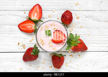 strawberry yogurt in a glass with fresh berries, oats and mint on white wooden background. healthy breakfast. top view Stock Photo
