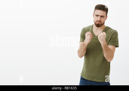 Man determined to fight calories after holidays. Portrait of handsome serious-looking angry bearded guy in t-shirt frowning making scary face as holding fists like boxer wanting punch and beat person Stock Photo