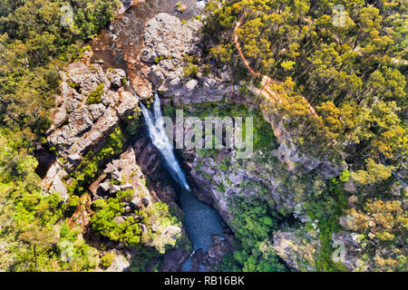 Stream of water on Kangaroo river falling down to eroded creek - beginning of Kangaroo valley known as Carrington falls in sandstone mountains. Aerial Stock Photo
