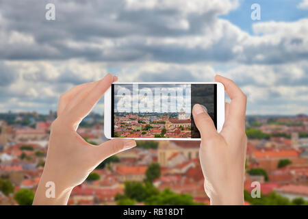 A man is making a photo of historical part of the city of Vilnius on a mobile phone. Stock Photo
