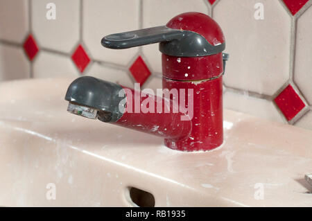 water leak out from red cap water tap in dirty washroom, selective focus Stock Photo