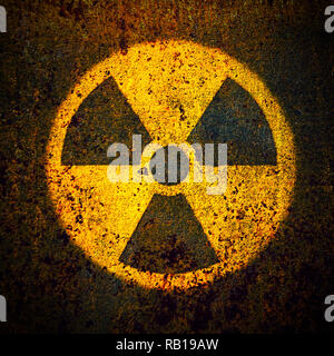 Round yellow radioactive (ionizing radiation) danger symbol painted on a massive rusty metal wall plate with dark rustic grungy texture background in  Stock Photo