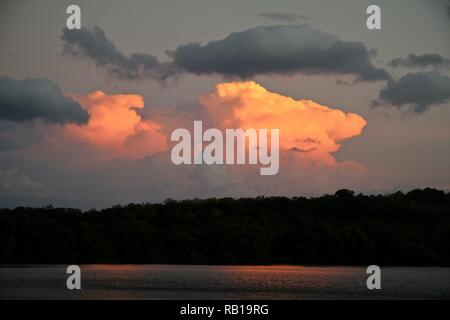 Gathering storm clouds at sunset illuminated pink and orange Stock Photo