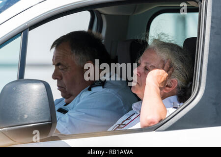 A couple of people looking bored and fed up, appearing to be parking wardens, sitting in a van seemingly looking out for victims, in the UK. Stock Photo