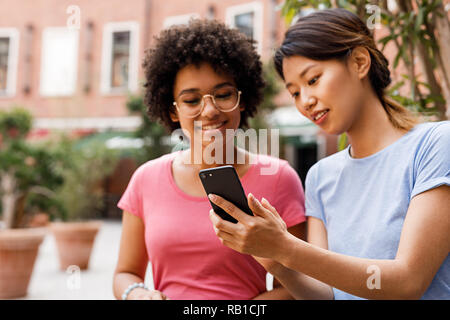 Two female friends looking at smartphone and talking Stock Photo