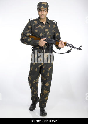 PORTRAIT OF INDIAN SOLDIER DRESSED IN UNIFORM HOLDING A HAND GUN