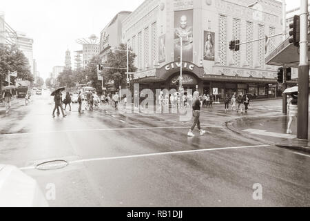 AUCKLAND NEW ZEALAND - DECEMBER 23 2018; People cross Queen Street and Wellesley Street intersection in front of historic Civic Theatre on wet day Stock Photo