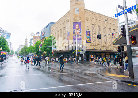 AUCKLAND NEW ZEALAND - DECEMBER 23 2018; People cross Queen Street and Wellesley Street intersection in front of historic Civic Theatre on wet day Stock Photo