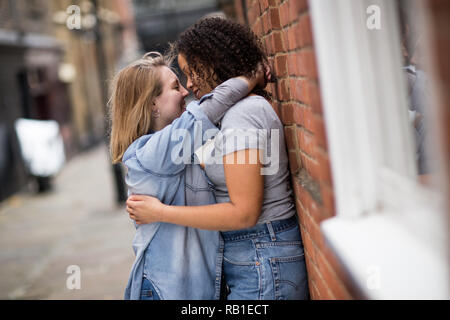 young candid lesbian kiss Lesbian couple at a cafe. Two young women are having a coffee together,  talking, cuddling and give each other a kiss. Candid situation with real  people. Homosexuality and lifestyle concepts.