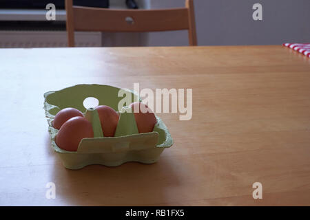 Brown eggs in a green cardboard box on a light wooden table Stock Photo