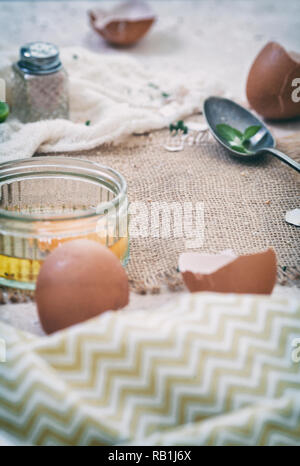 Raw hen egg and empty cracked shells on the top of kitchen table Stock Photo